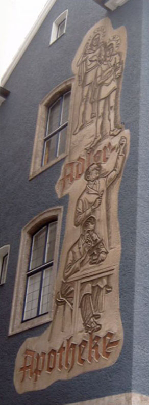 Sgrafittobild zeigt mehrere Figuren und den schriftzug Adler Apotheke